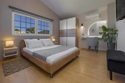 a bedroom with a large bed and a chair at Coral Paradise Luxury Modern Family Villa with Jacuzzi, Pool View & Parking in Rhodes Island in Kremasti
