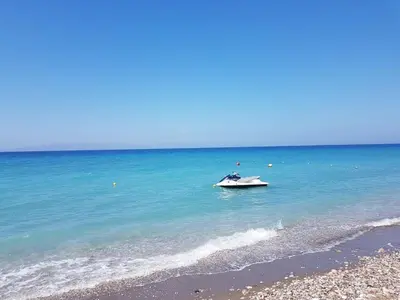a boat sitting in the water on a beach at Coral Paradise Luxury Modern Family Villa with Jacuzzi, Pool View & Parking in Rhodes Island in Kremasti