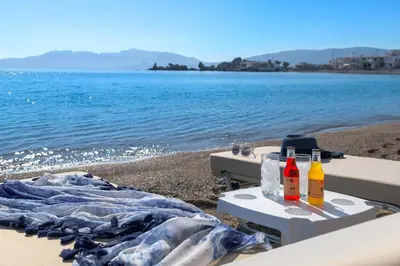 a picnic table on the beach with drinks on it at Villa Haraki Paradise in Haraki