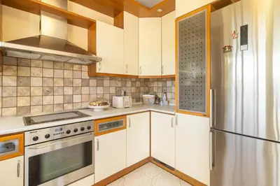 a kitchen with white cabinets and a stainless steel refrigerator at Erofili's Apartment ONLY 700 meters from the beach in Ialyssos