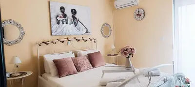 a bedroom with a white bed with pink pillows at Erofili's Apartment ONLY 700 meters from the beach in Ialyssos