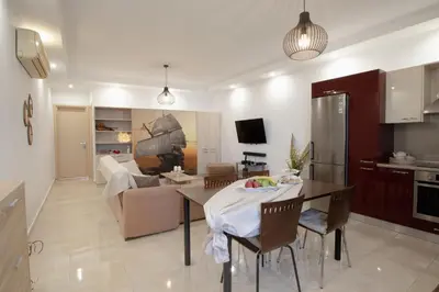 a kitchen and a living room with a table and chairs at Pearl of Stegna - Beach House in Archangelos