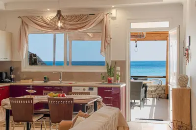 a kitchen and dining room with a view of the ocean at Pearl of Stegna - Beach House in Archangelos
