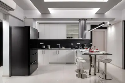a kitchen with white cabinets and a table with stools at Rhodes Skyline Suite with In Door Jacuzzi Sea View in Ixia