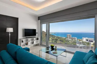 a living room with a blue couch and a large window at Rhodes Skyline Suite with out Door Jacuzzi Sea View in Ixia