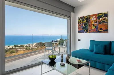 a living room with a blue couch and a large window at Rhodes Skyline Suite with out Door Jacuzzi Sea View in Ixia