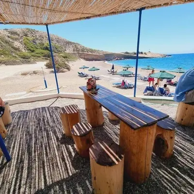a wooden bench on a beach with a view of the ocean at Arsithea Villa in Monólithos