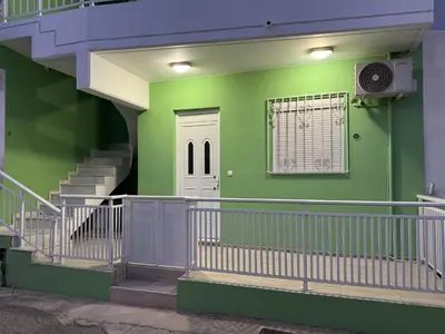 a green building with stairs and a white door at Aesthetic Cozy Haven in Kremasti