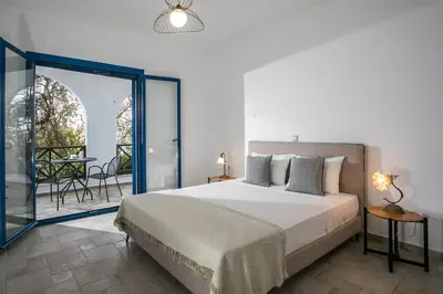 a bedroom with a bed and a balcony with a table at Villa Kaya in Haraki