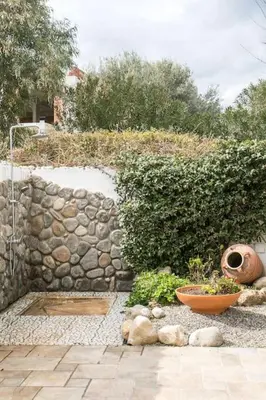 a garden with a stone wall and some plants at Villa Kaya in Haraki