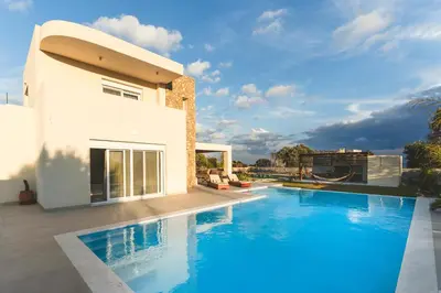 a swimming pool in front of a house at Cleopatras Villa in Lachania