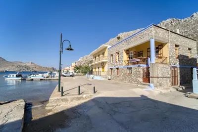 a building with a street light next to a body of water at Waterfront House Pedi in Symi