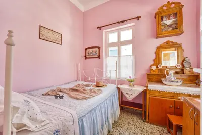 a bedroom with a bed and a dresser and a window at Waterfront House Pedi in Symi