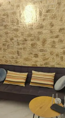 a black couch with pillows and a brick wall at Villa Marina, apartment Hara, Rodos in Ixia