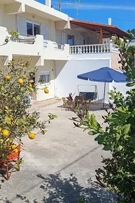 a house with a patio and an umbrella and some trees at Rhodes Volkshaus in Afantou