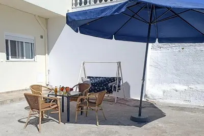 a table and chairs under a blue umbrella at Rhodes Volkshaus in Afantou
