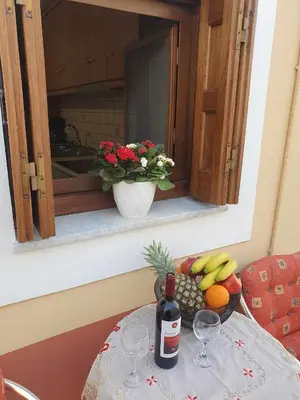 a table with a bowl of fruit and a bottle of wine at Aggeliki's House in Symi