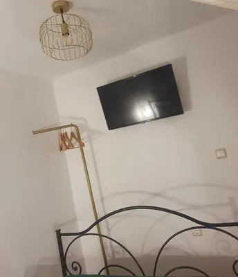 a room with a tv on the wall and a lamp at Aggeliki's House in Symi