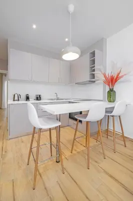 a kitchen with white cabinets and a table and chairs at Sky Char Ialysos in Ialyssos