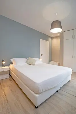 a bedroom with a large white bed and a lamp at Sky Char Ialysos in Ialyssos