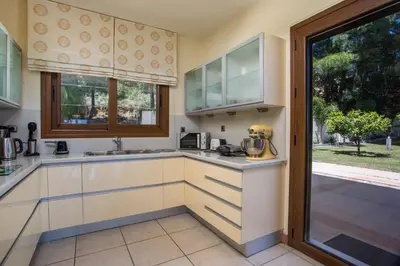 a kitchen with white cabinets and a window at Luxury Villa Amaltheia Rhodes in Koskinou
