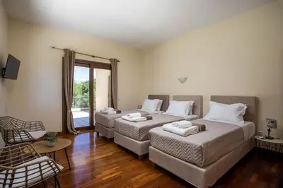 a room with two beds and a couch and a window at Luxury Villa Amaltheia Rhodes in Koskinou