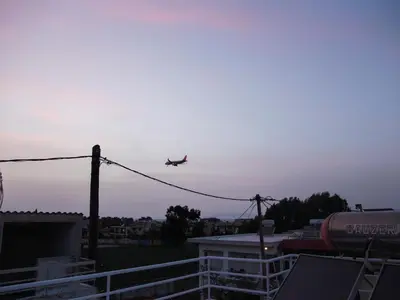an airplane flying in the sky over a city at SunView Studio in Kremasti