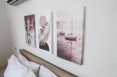a group of four pictures on a wall above a bed at SunView Studio in Kremasti