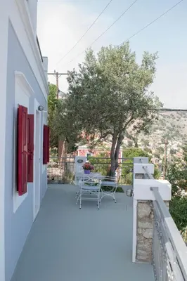 a balcony of a white building with chairs and a tree at Marea Studios in Symi