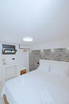 a bedroom with a white bed and a brick wall at Casa Napais Earth Retreat in Archangelos