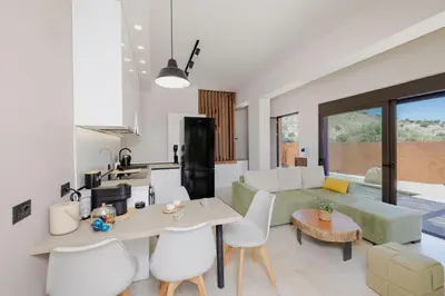 a kitchen and living room with a table and chairs at Casa Napais Earth Retreat in Archangelos