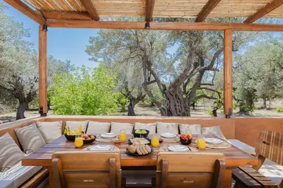 a wooden table with food on it on a patio at Casa Napais Earth Retreat in Archangelos