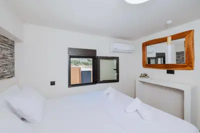 a white bedroom with two beds and a window at Casa Napais Earth Retreat in Archangelos