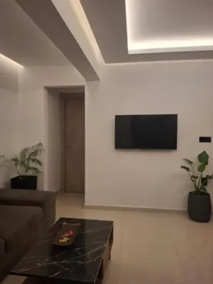 a living room with a couch and a tv on the wall at Prifti Luxury apartment in Faliraki