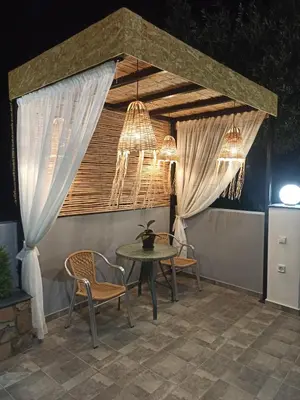 a patio with a table and chairs and chandeliers at Paradise Apartment, Lardos Village in Lardos