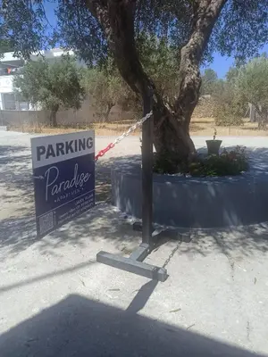 a parking sign next to a tree next to a street at Paradise Apartment, Lardos Village in Lardos