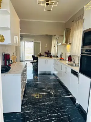 a kitchen with white cabinets and black marble floors at Flev's House with Jacuzzi & Rooftop BBQ in Kremasti