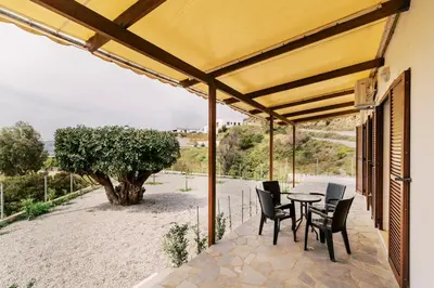 a patio with a table and chairs and a tree at Alonia View House in Asklipiḯon
