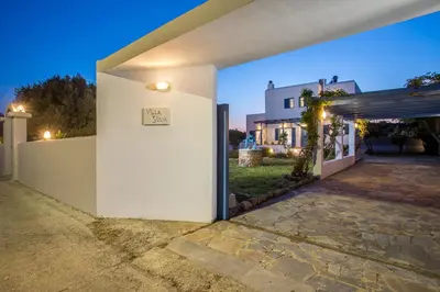 a white building with a door with a sign on it at Traditional Greek Island Summer at Villa Julia in Kolimbia