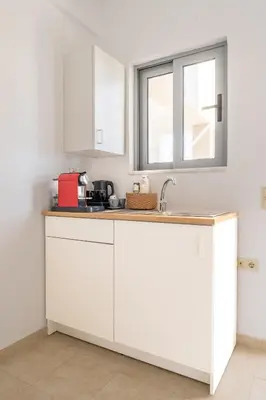 a kitchen with white cabinets and a window at Alpha Urban Suites in Rhodes Town