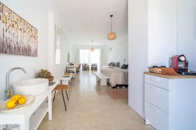 a white kitchen with a sink and a living room at Alpha Urban Suites in Rhodes Town