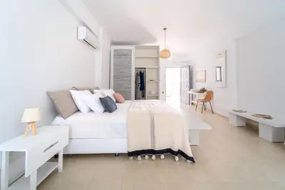 a white bedroom with a white bed and a desk at Alpha Urban Suites in Rhodes Town