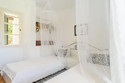 a white bedroom with a bed and a window at Los Olivos V.I.P Poolvilla Kritinia in Kamiros