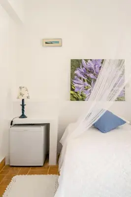 a white bedroom with a white bed with a blue pillow at Los Olivos V.I.P Poolvilla Kritinia in Kamiros