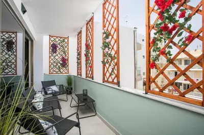 a balcony with chairs and windows with red flowers at Luciana City Apartment in Rhodes Town