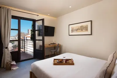 a bedroom with a bed and a balcony with a desk at Fluvian Terrace in Rhodes Town