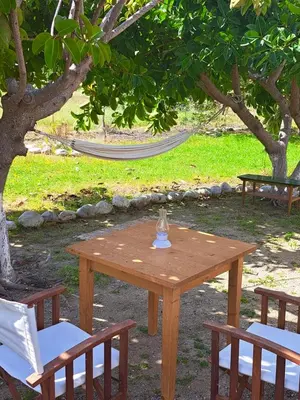 a wooden table and two chairs and a hammock at Lovely independent room in Ecovilla on the beach in Apolakkiá