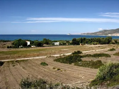 an empty field with the ocean in the background at Lovely independent room in Ecovilla on the beach in Apolakkiá
