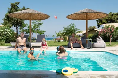 a group of people in a swimming pool with umbrellas at Let it Be Apartments in Theologos