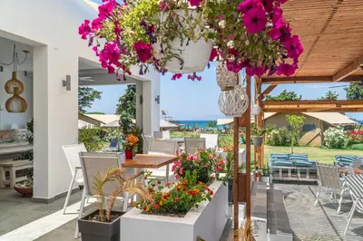 a patio with flowers and a table and chairs at Let it Be Apartments in Theologos